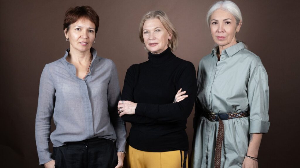 3 dojrzałe kobiety przedstawiają stylizacje do pracy i na co dzień.