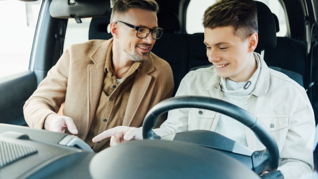 Ojciec razem z synem siedzą w samochodzie, który ojciec chce podarować synowi.